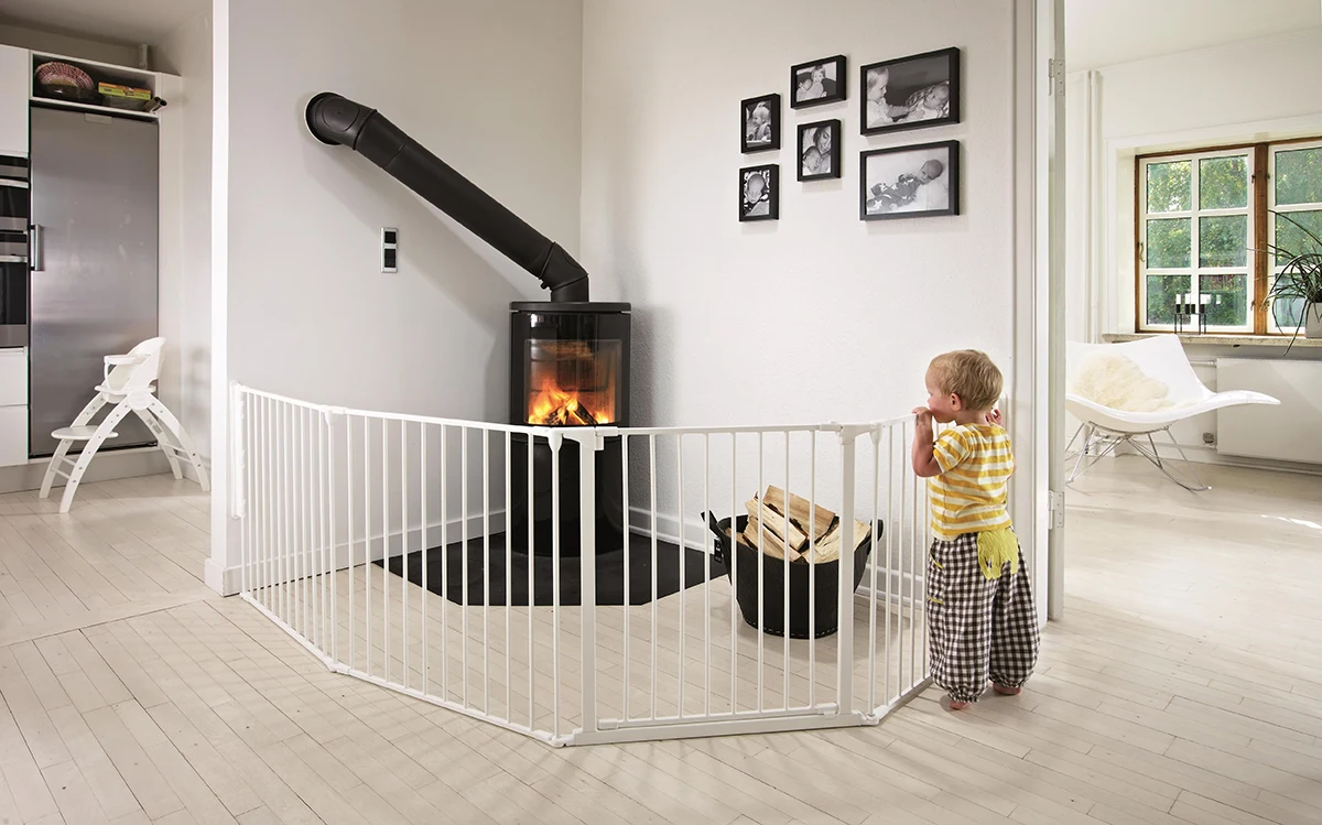 Child near a wood-burning stove with a fireplace guard